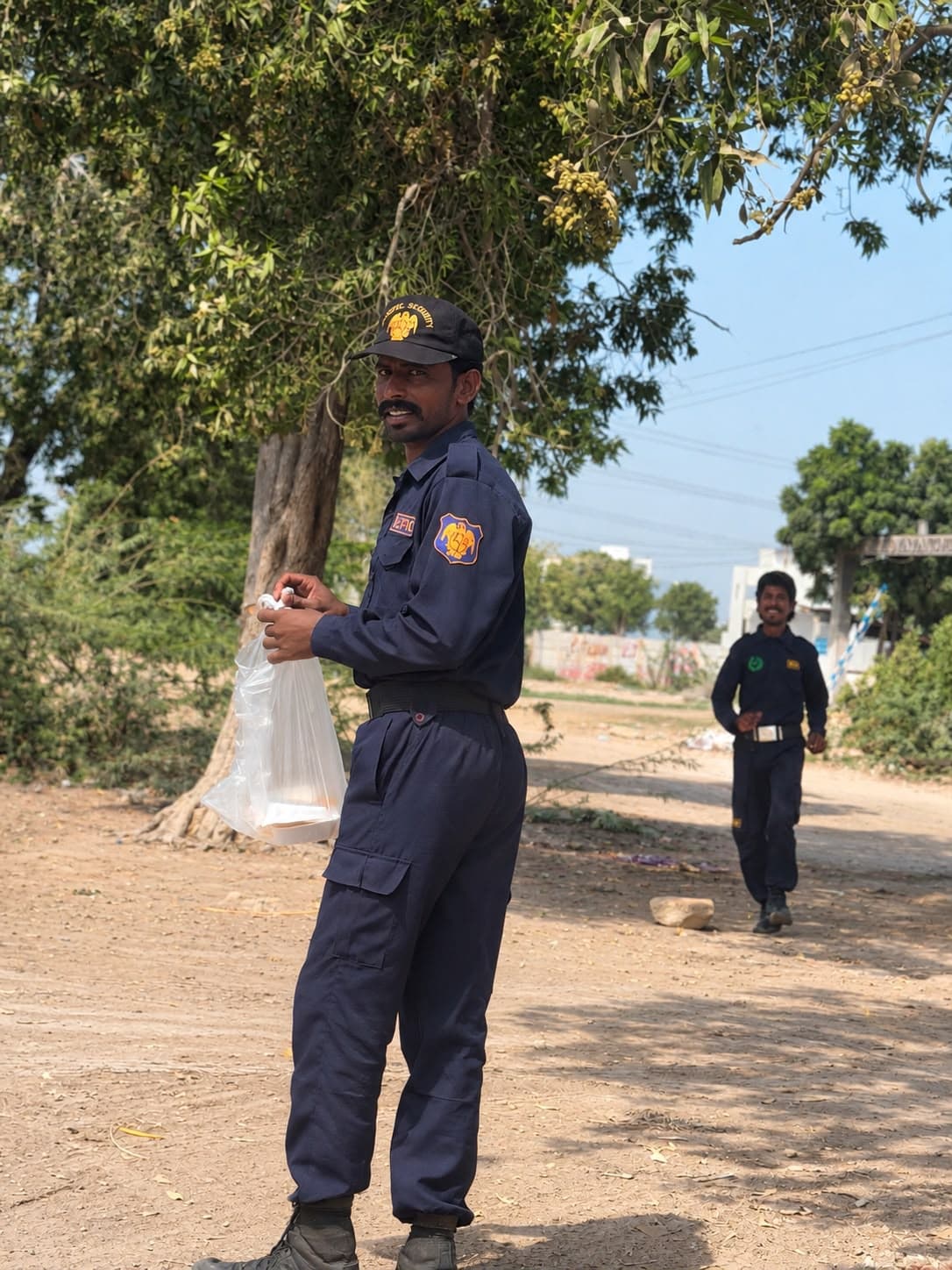 A security guard in uniform holding the meal he was given on his shift