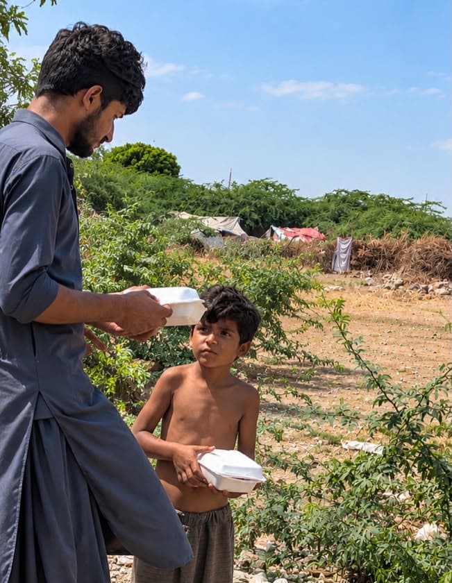 A volunteer passing a meal box to a young boy